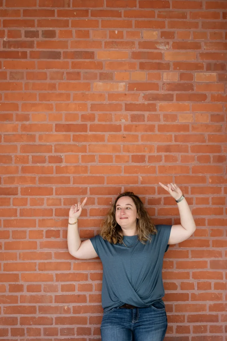 Kristen Jerry laughing against a red brick wall