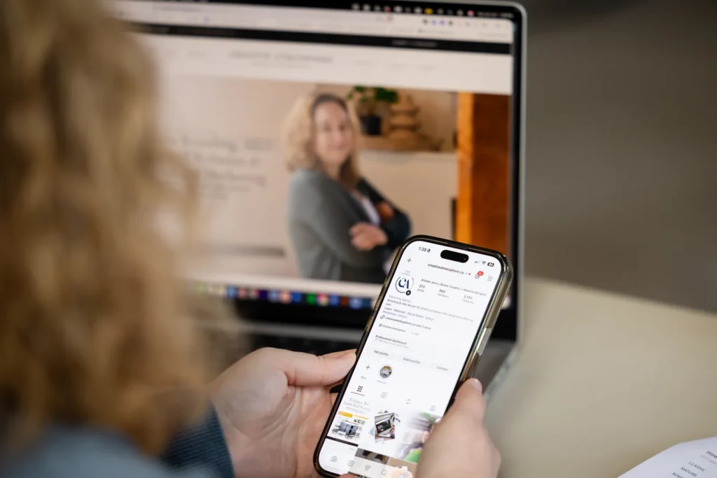 Checking social media on a phone in front of a laptop