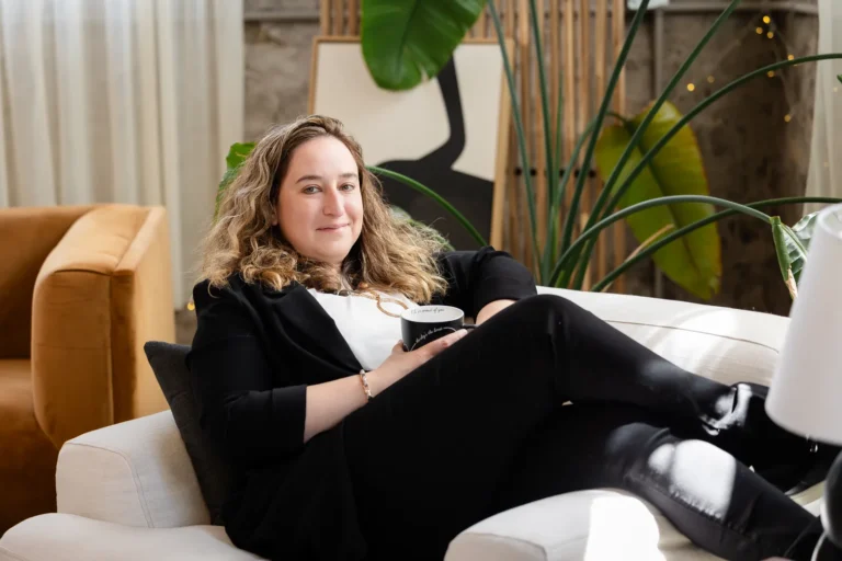 Kristen Jerry smiling on a sofa with a coffee mug