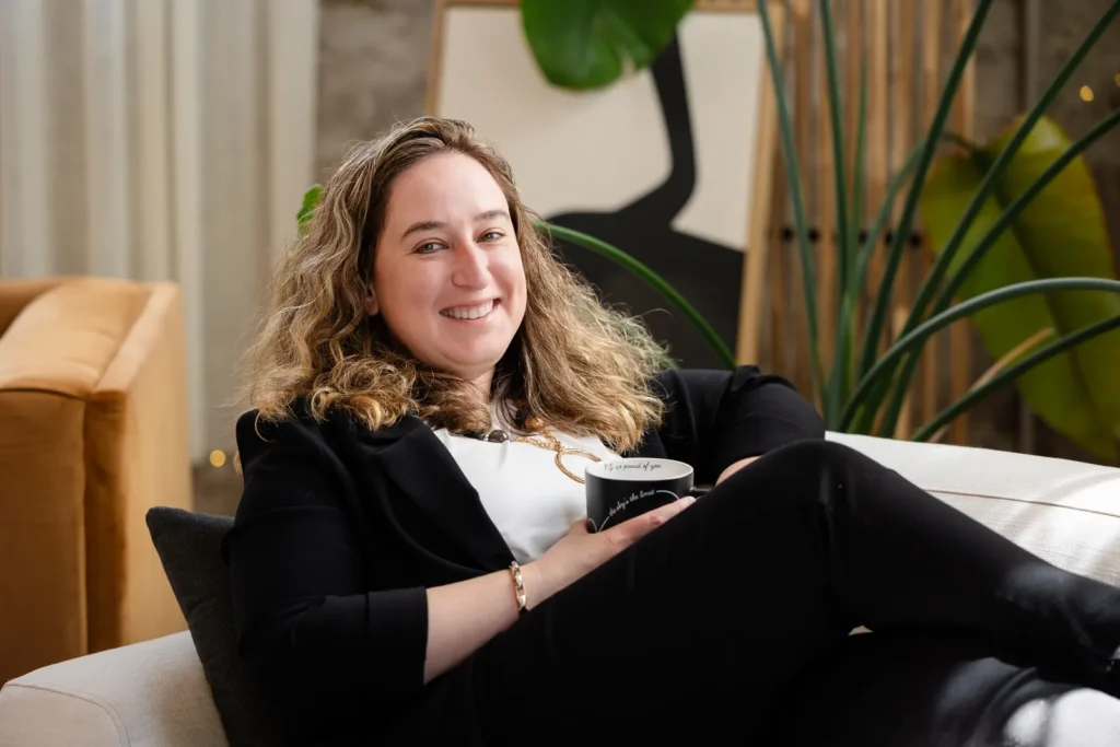 Kristen Jerry smiling on a sofa with a mug