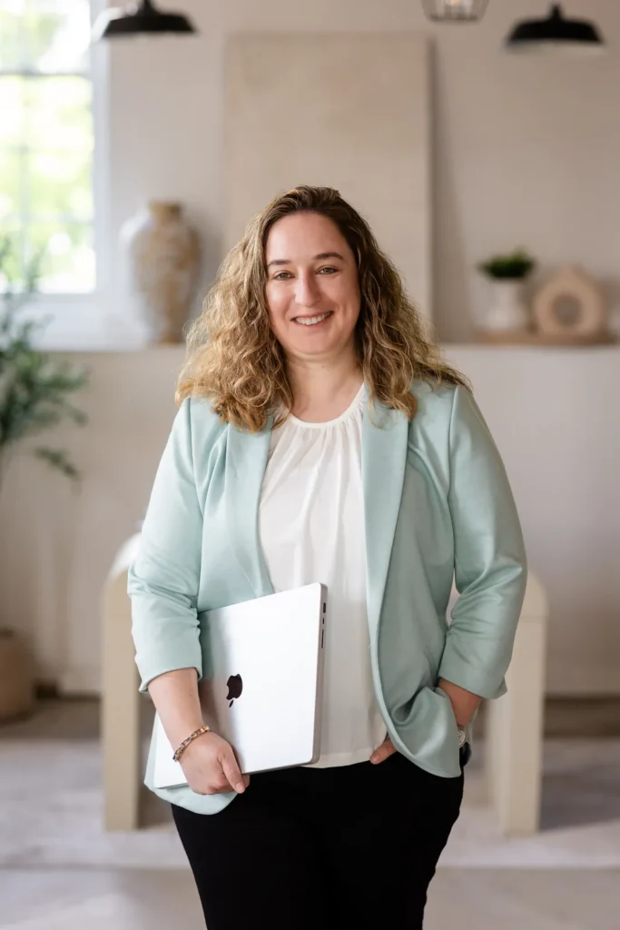 Kristen Jerry standing in her studio holding a laptop