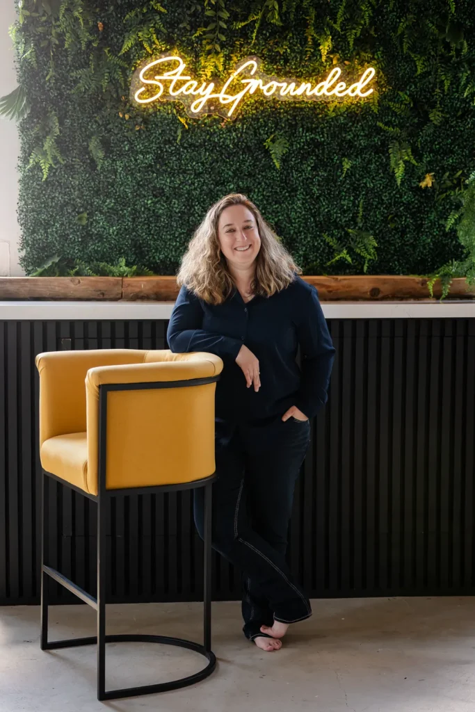 Kristen Jerry under a Stay Grounded neon sign