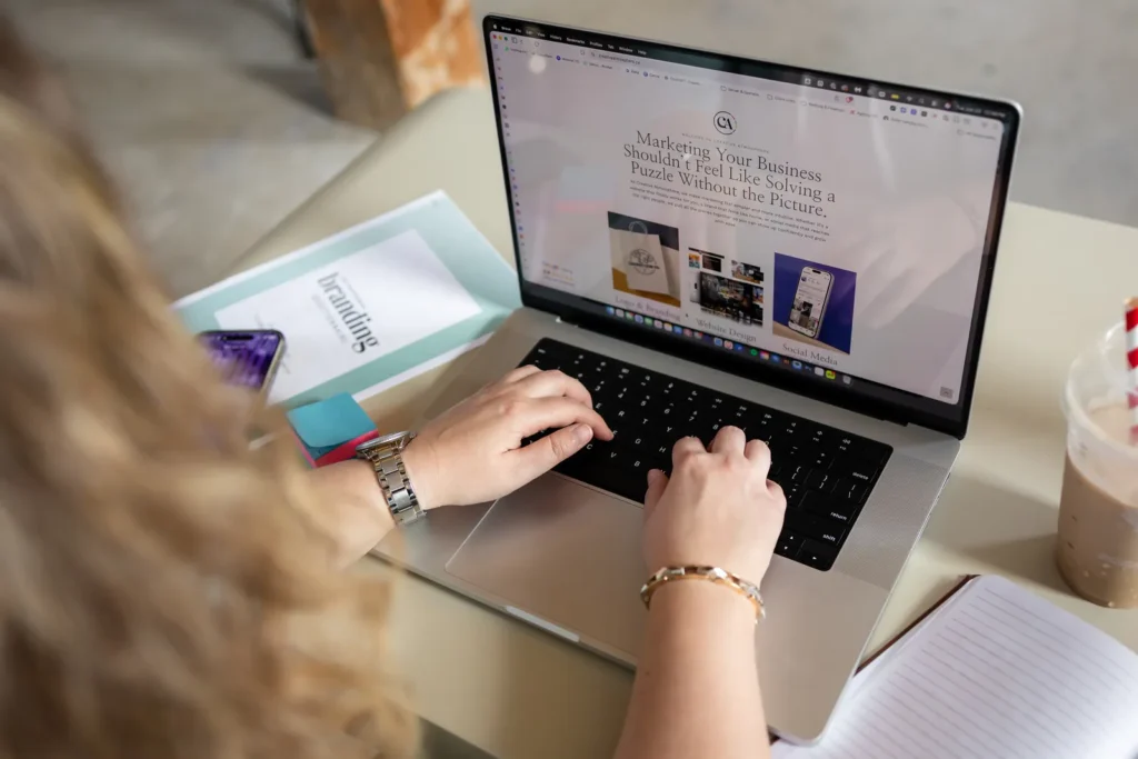 Hands typing on a laptop showing a website design