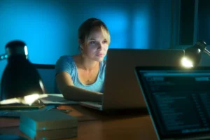 Woman writing on laptop computer late at night